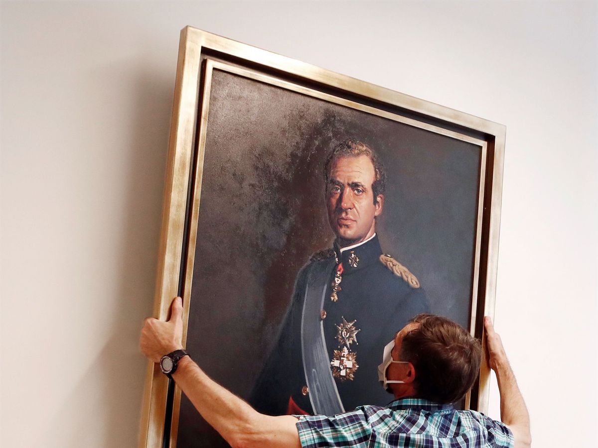 Foto: Un empleado del Parlamento retira de la "sala de gobierno" el retrato de Juan Carlos I. (EFE)