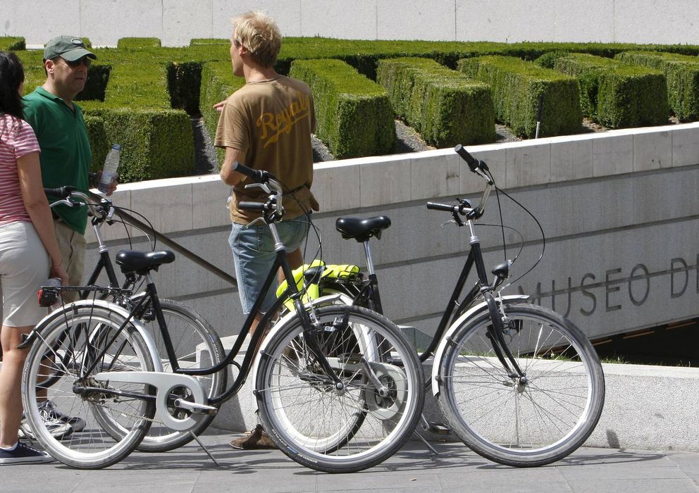 Foto: Unos jóvenes turistas descansan para recuperarse del calor con sus bicicletas alquiladas junto al Museo del Prado. (EFE)