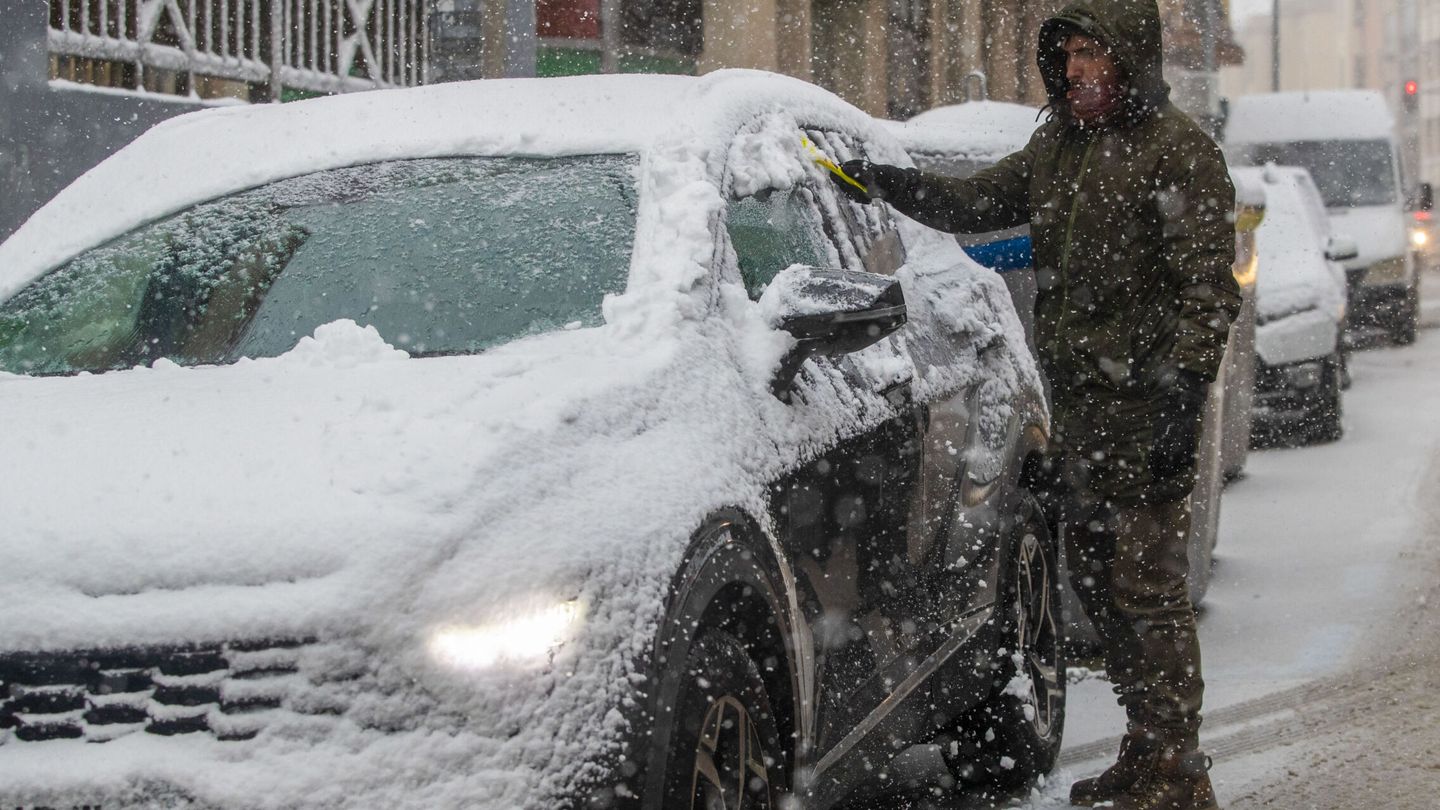 Un chico quitando nieve de su coche en Soria. (EFE)