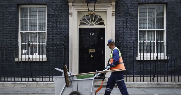 Foto: Un empleado de la limpieza pasa ante el nº 10 de Downing Street. (EFE)