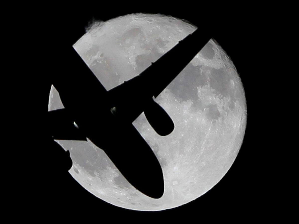 Foto: Un avión vuela bajo la Luna. (Reuters)