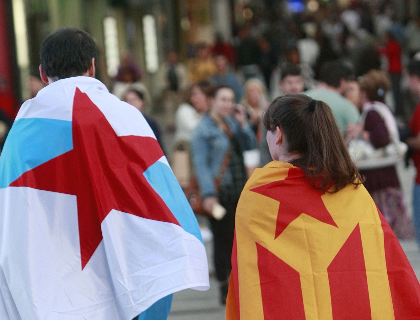 Una pareja porta las banderas independentistas gallega y catalana. (EFE)