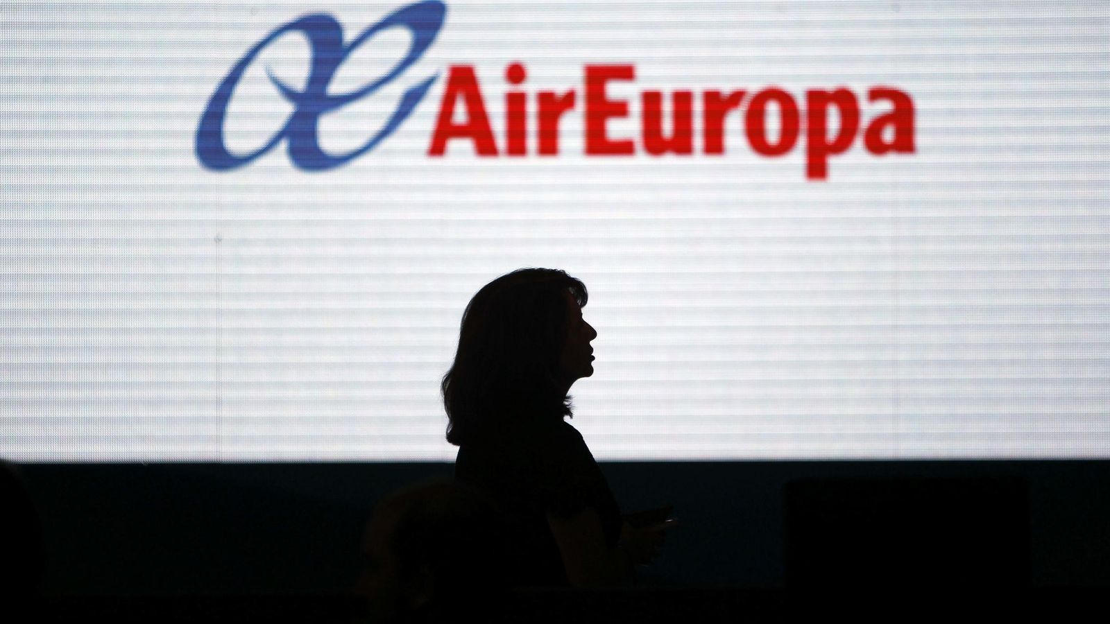 Foto: La silueta de una mujer se dibuja sobre una pantalla con el logotipo de Air Europa. (EFE)