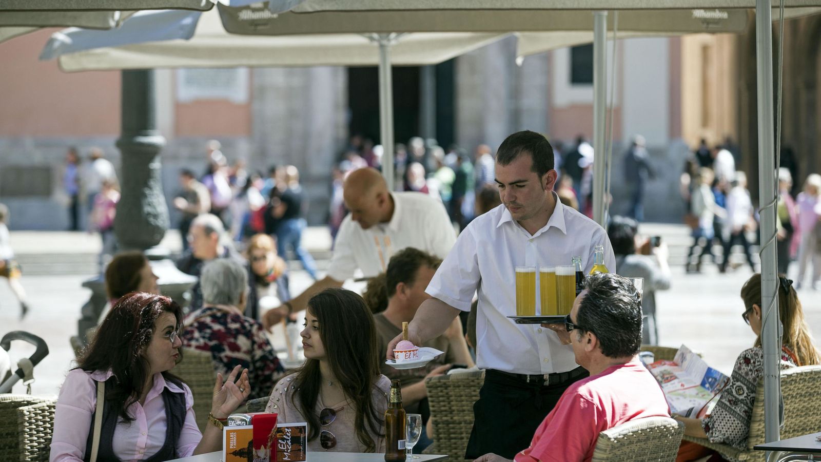 Foto: Un camarero sirve bebidas en una terraza en la plaza de la Virgen de Valencia. (EFE)