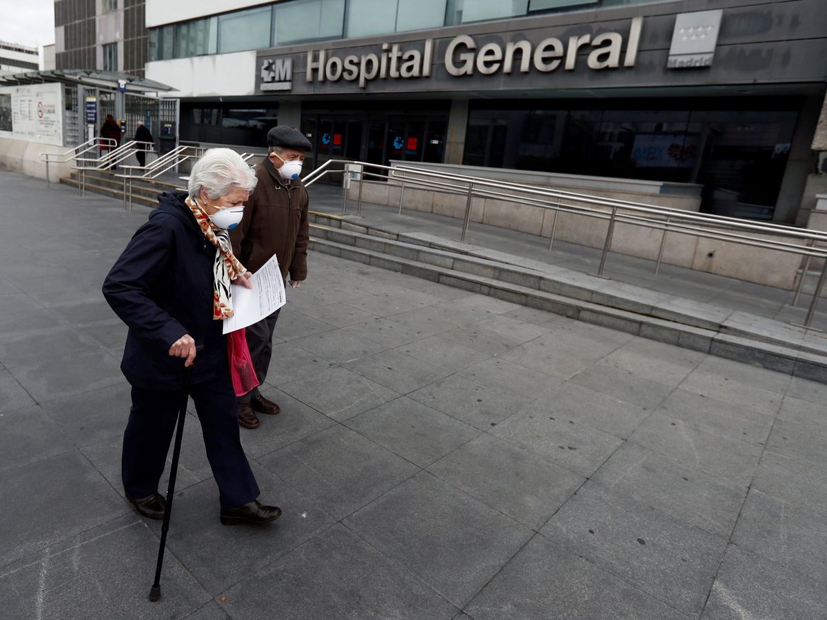 Foto: Una pareja de ancianos pasa ante el Hospital de La Paz, en Madrid. (EFE)