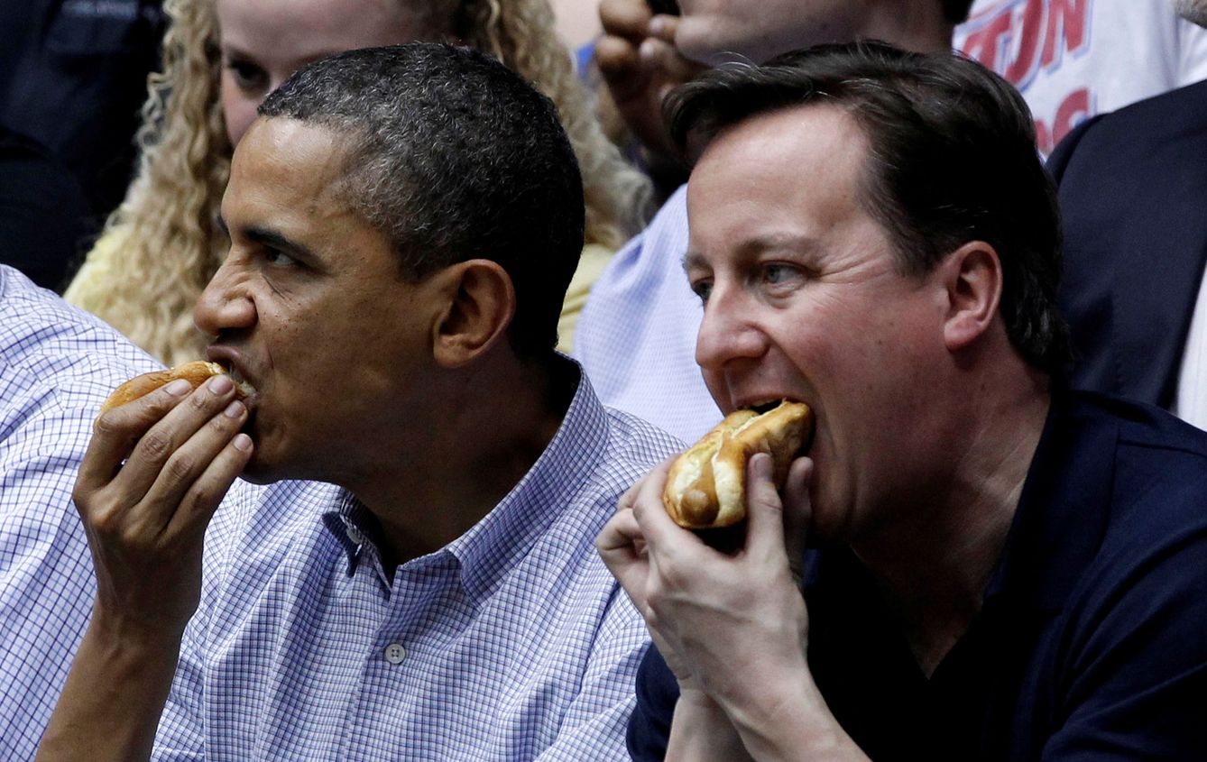 Barack Obama y David Cameron comen un perrito caliente en un partido de baloncesto. (EFE)