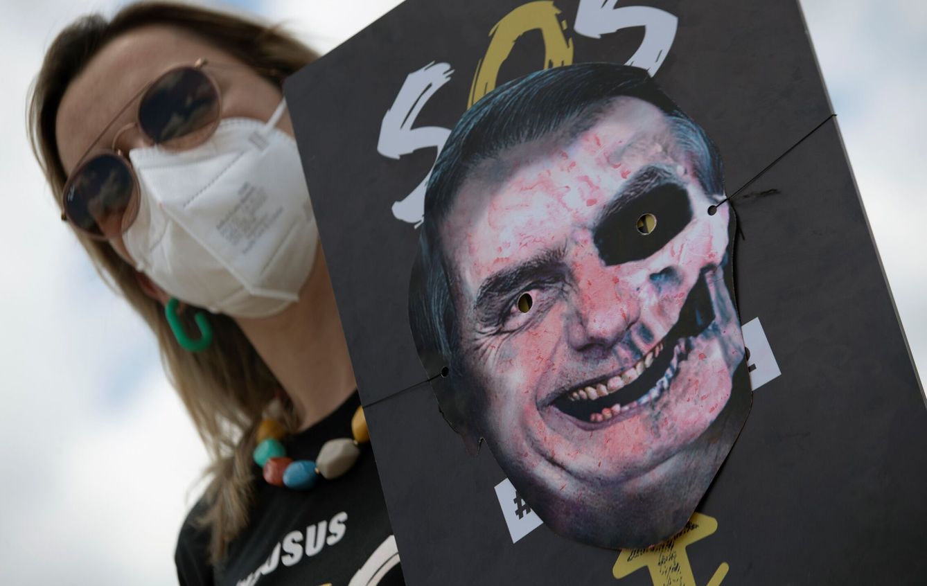 Una mujer sostiene un cartel con una imagen que representa al presidente de Brasil, Jair Bolsonaro, pintado como una calavera. (EFE)