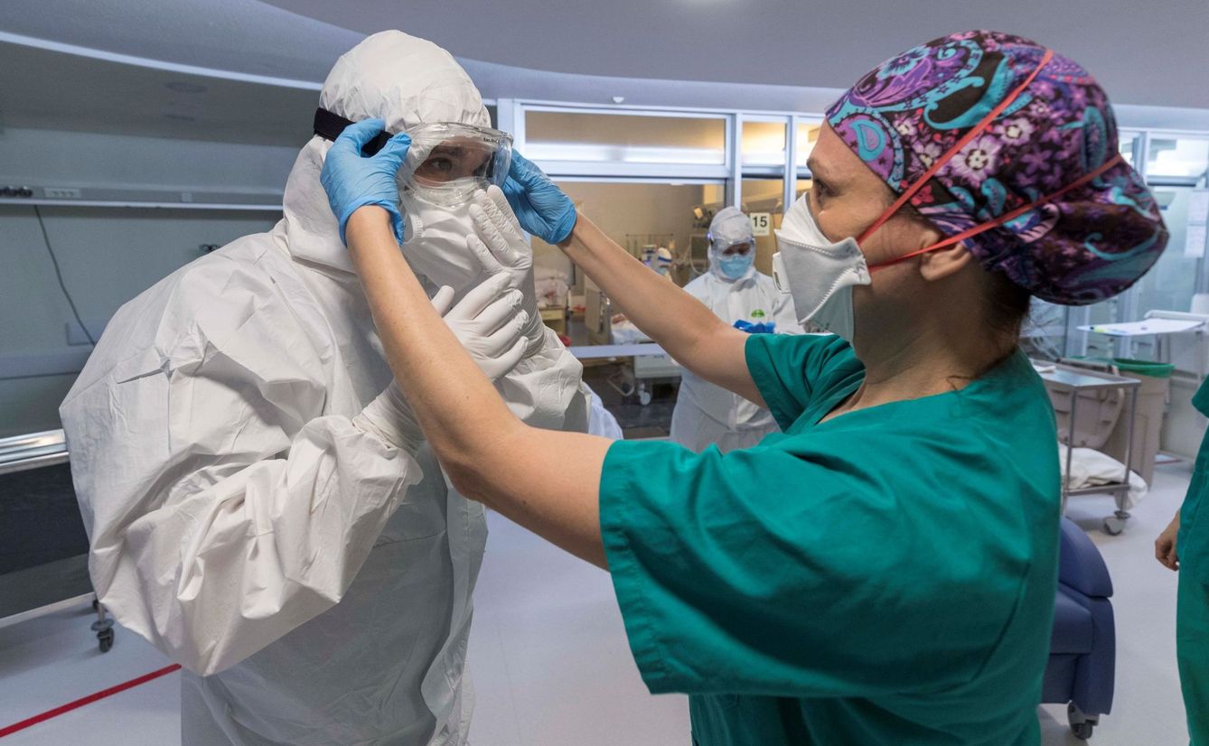 Una enfermera de la unidad de cuidados intensivos (UCI), ayuda a un compañeros a colocarse las protecciones necesarias antes de entrar en un box para atender a un paciente infectado con COVID 19, en el hospital universitario Morales Meseguer de Murcia. (EFE)