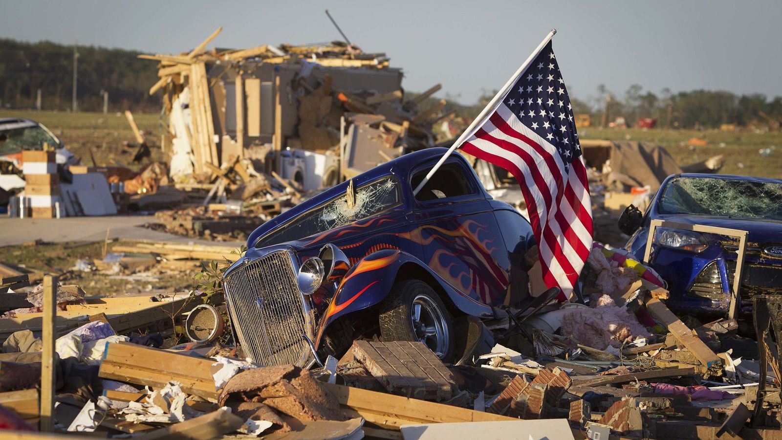 Foto: Una bandera de EEUU sale de la ventana de un coche destrozado por un tornado en Vilonia, Arkansas, en abril de 2014. (Reuters)