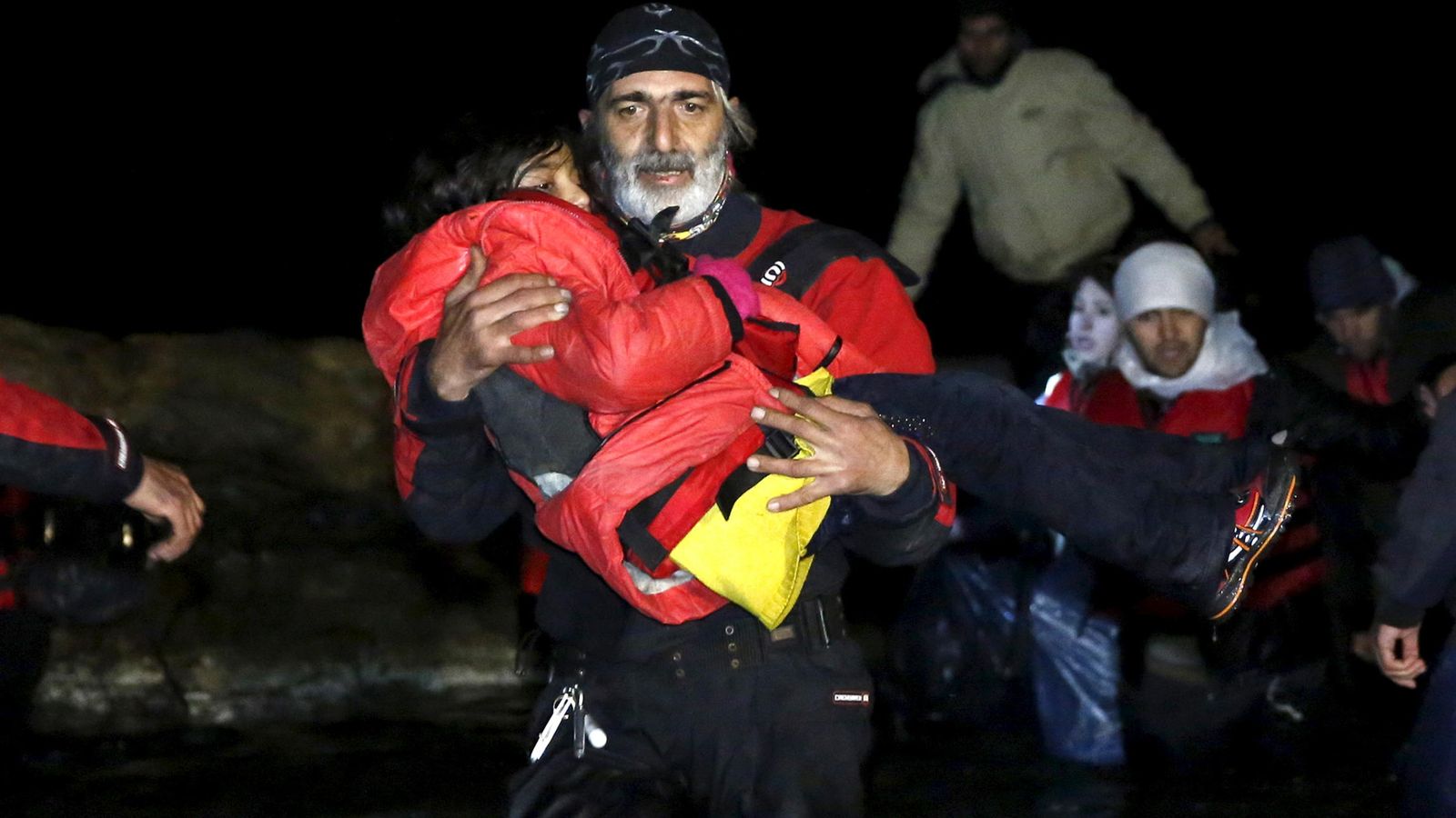 Foto: Un voluntario carga con un menor tras la llegada de un grupo de afganos a las costas de la isla griega de Quíos (Reuters).