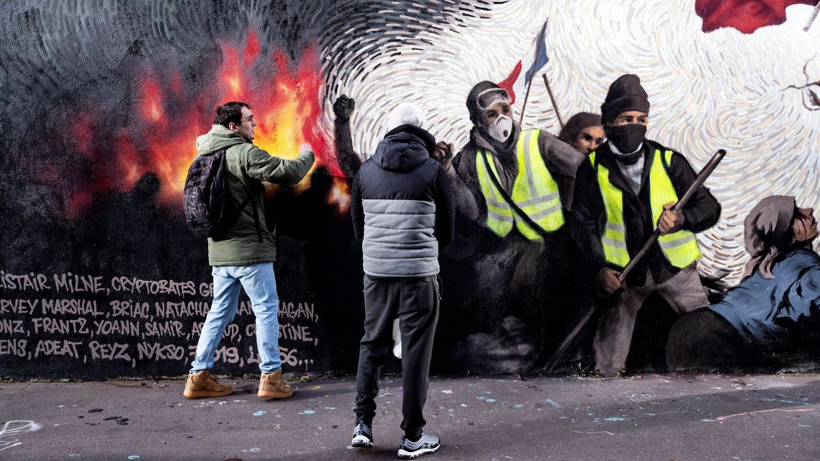 Foto: Dos jóvenes buscan pistas para obtener una recompensa en un mural del artista francés Pascal Boyart sobre los 'chalecos amarillos', en París. (EFE)