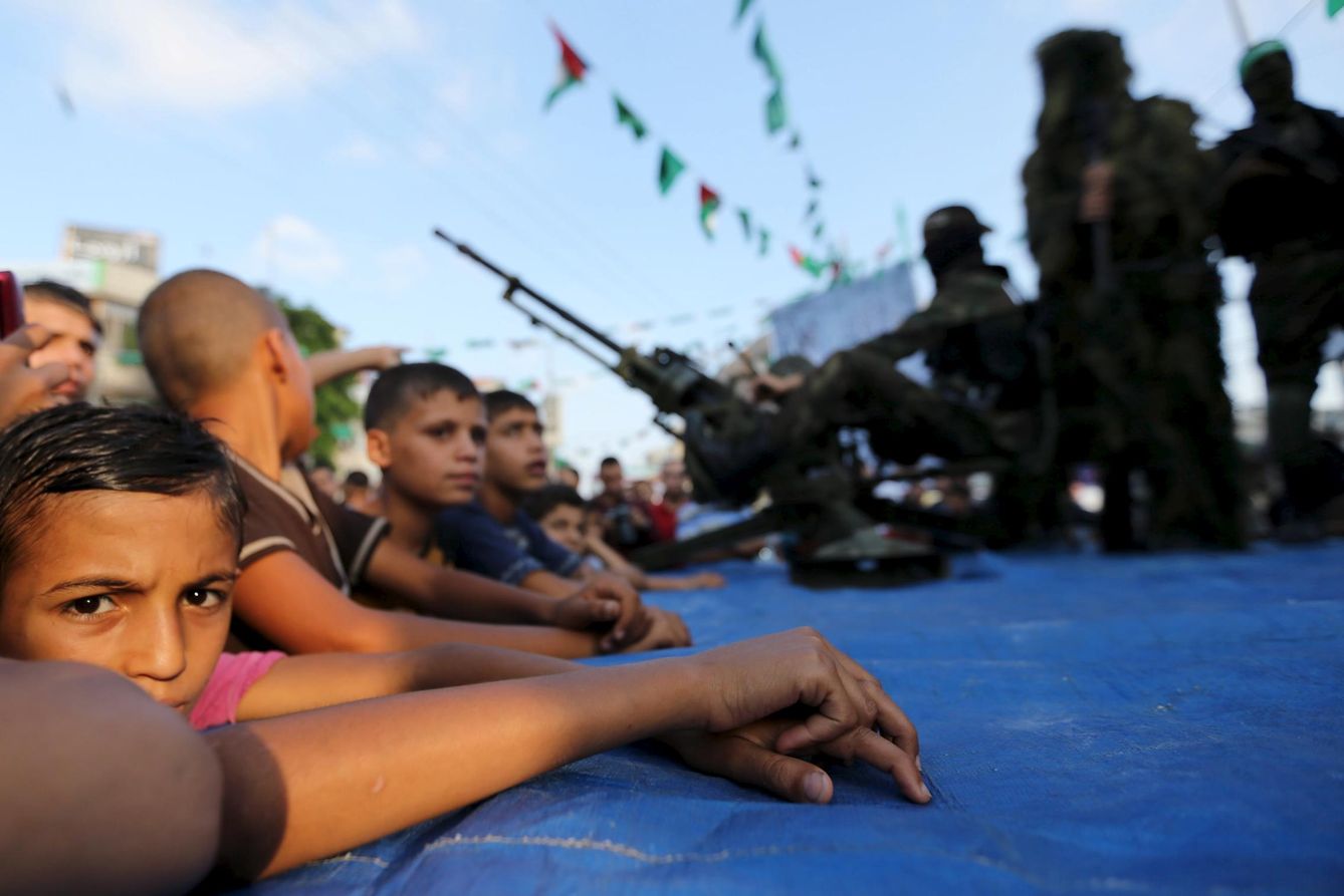 Niños palestinos observan a miembros de las brigadas Al Qassam, el brazo armado de Hamás, en Rafah, Gaza (Reuters).