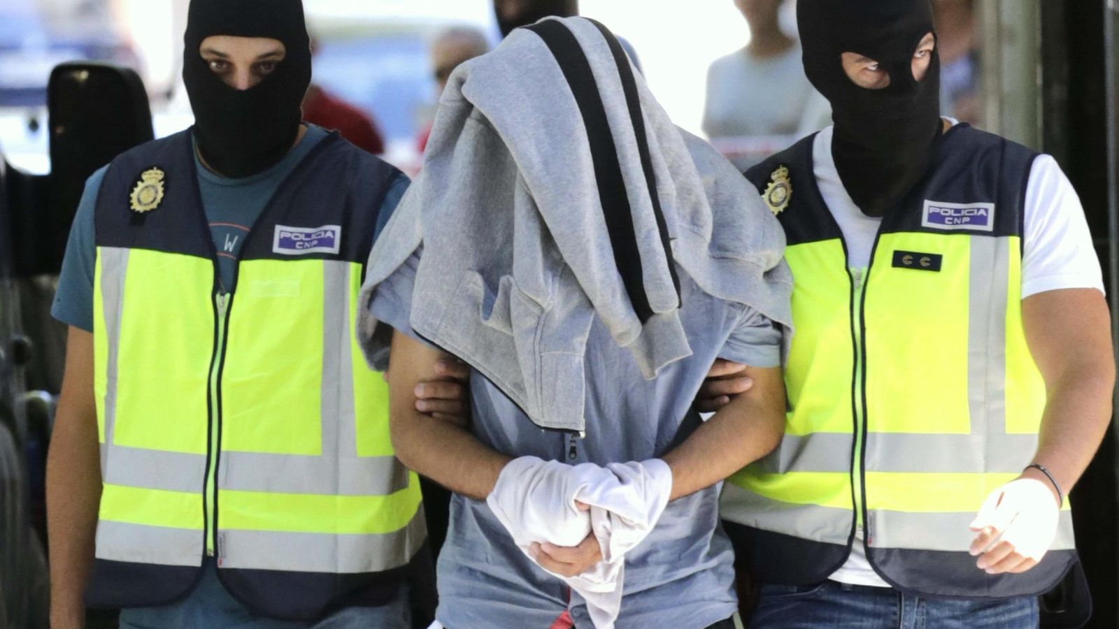 Foto: Agentes de la Policía Nacional conducen al detenido con la cabeza tapada. (EFE)