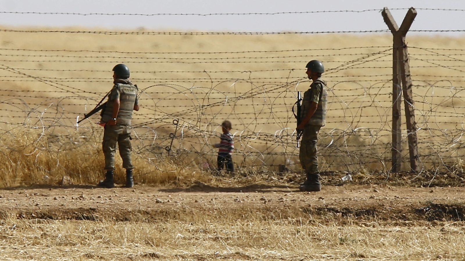 Foto: Soldados turcos montan guardia mientras un niño sirio observa desde el otro lado de la frontera en Akçakale, en junio de 2015 (Reuters)