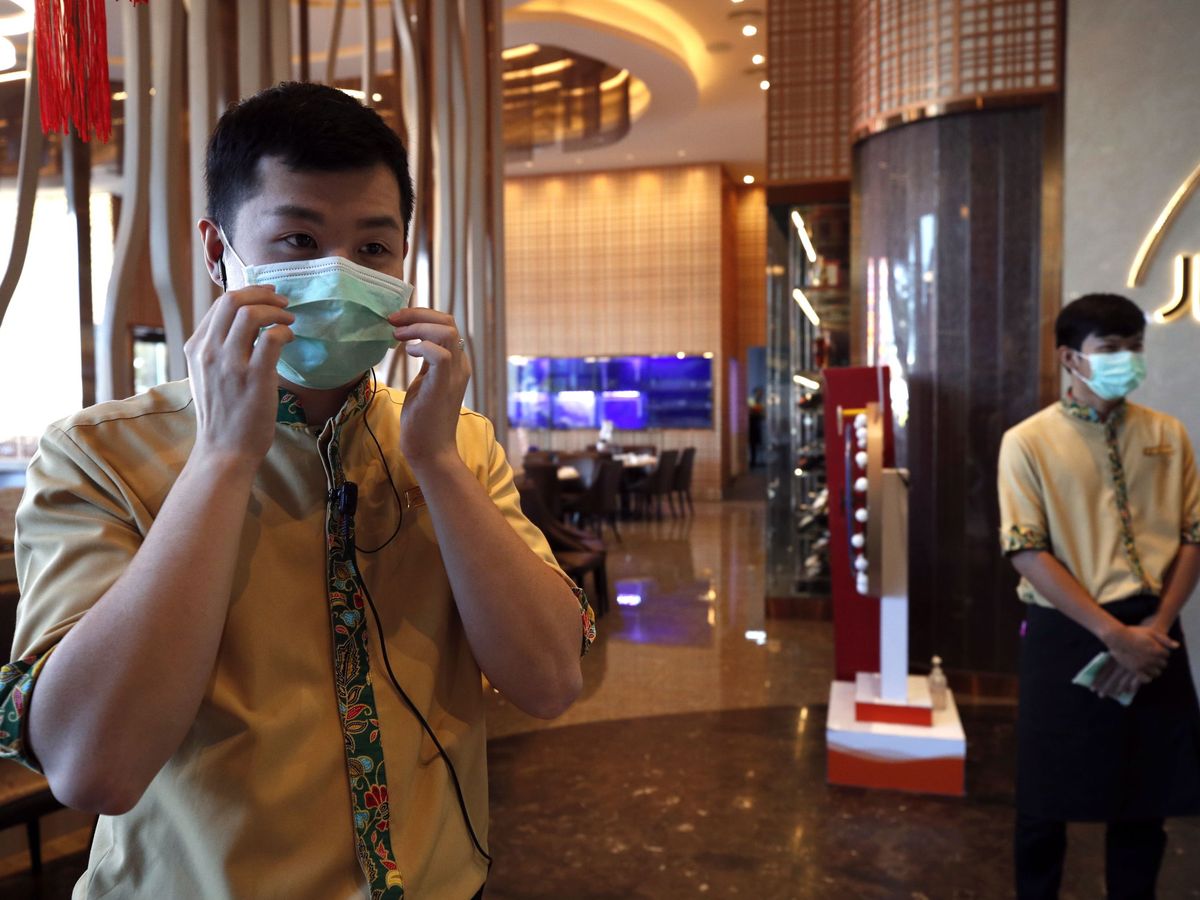 Foto: Dos camareros con mascarilla para evitar el contagio del coronavirus, en Tailandia. (Reuters)