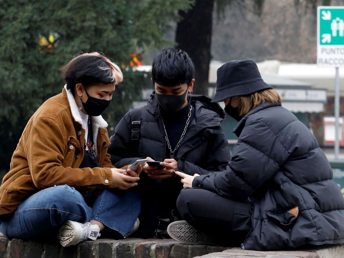 Foto: Varios jóvenes con máscaras protectores revisan sus teléfonos móviles este martes en Milán (EFE).