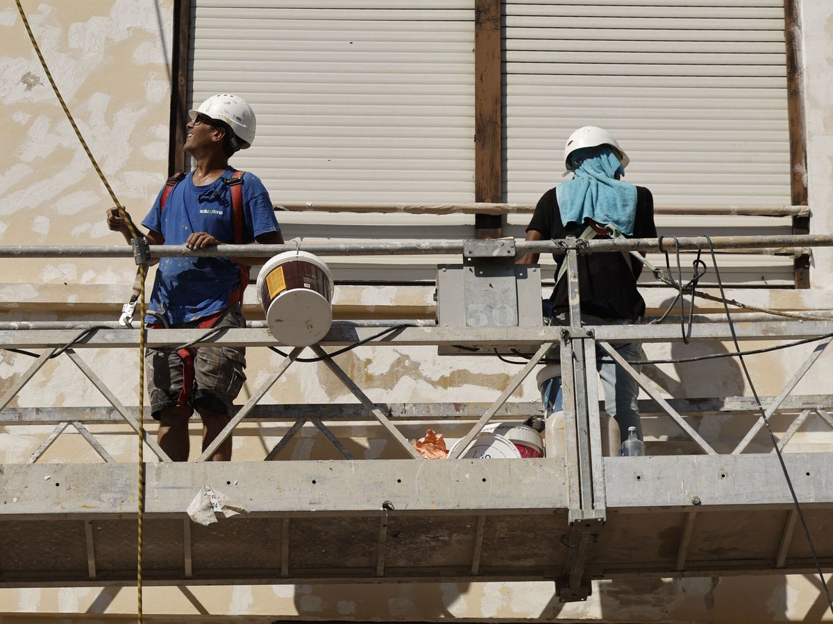 Foto: Dos trabajadores en un andamio. (EFE/Biel Aliño)