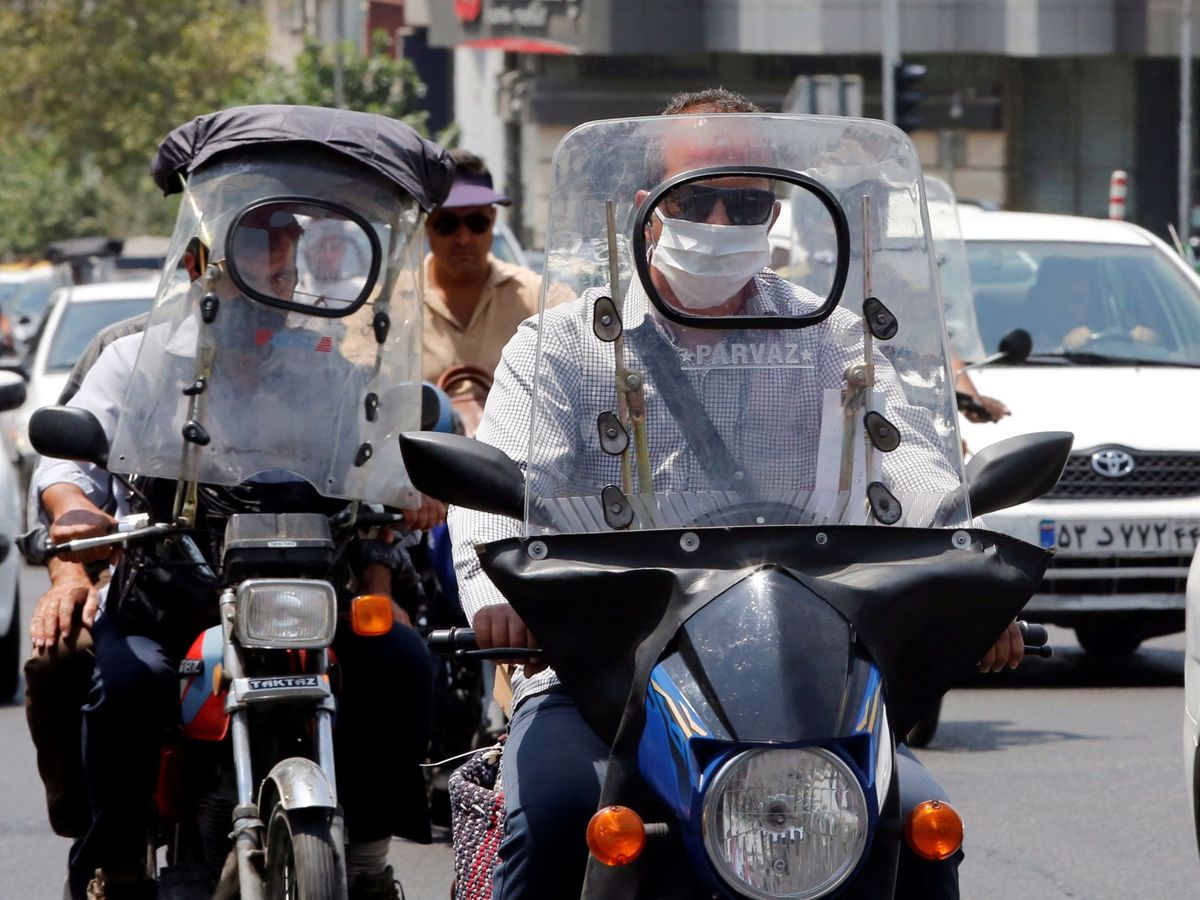 Foto: Dos motoristas protegidos con sendas máscaras circulan por una calle en Teherán, Irán. (EFE)