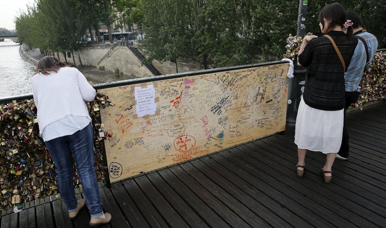 Varios turistas se acercan a la tabla colocada para reemplazar la hundida barandilla del Pont des Arts.