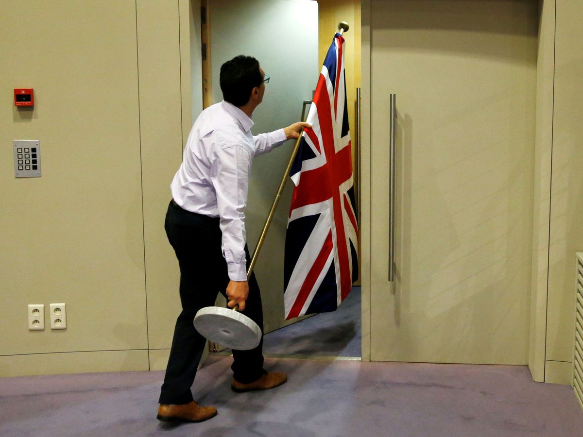 Foto: Un funcionario europeo carga con una bandera británica antes de una rueda de prensa. (Reuters)