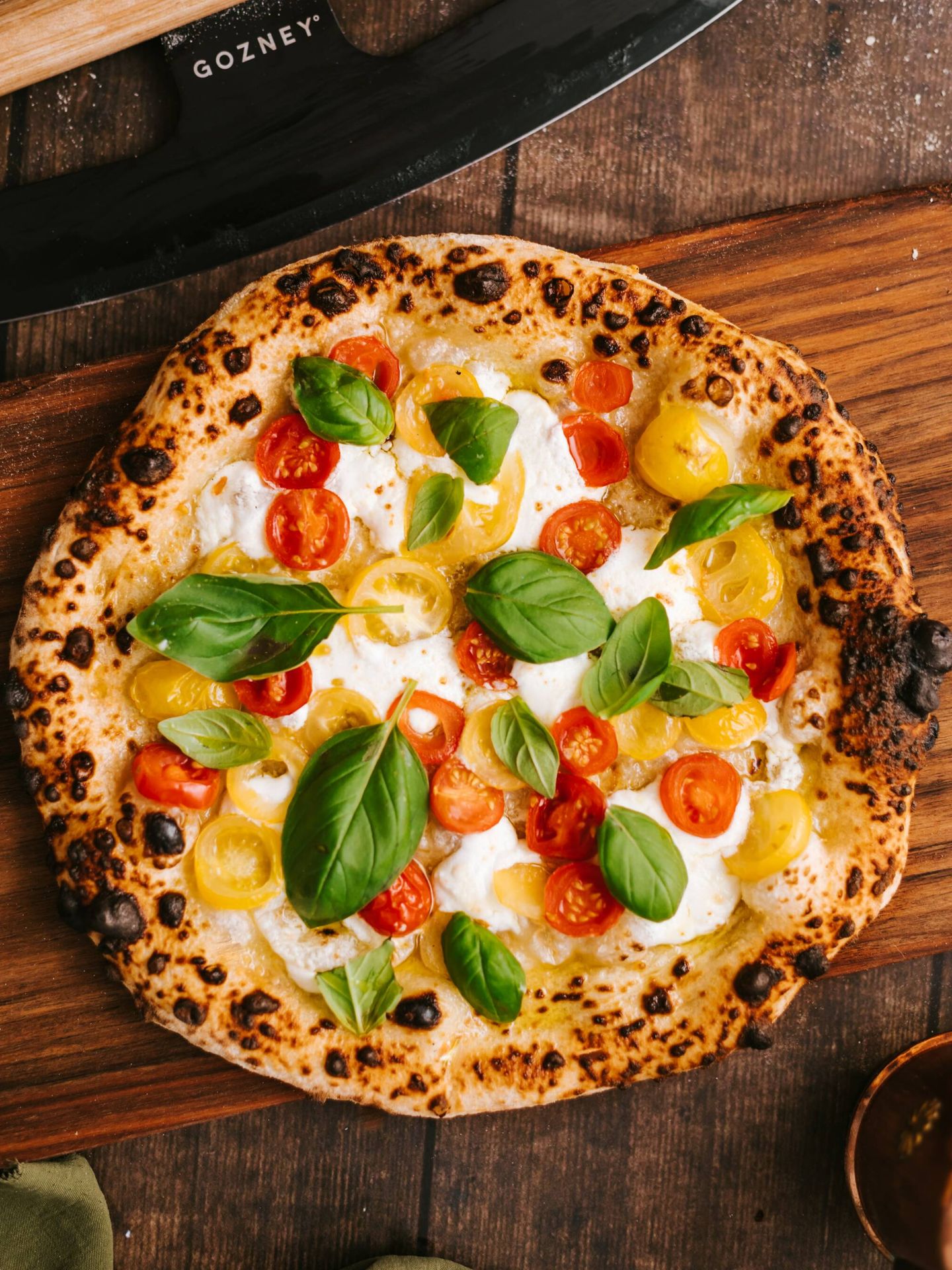 Pizza tradicional con queso, cherry y albahaca. (Pexels)