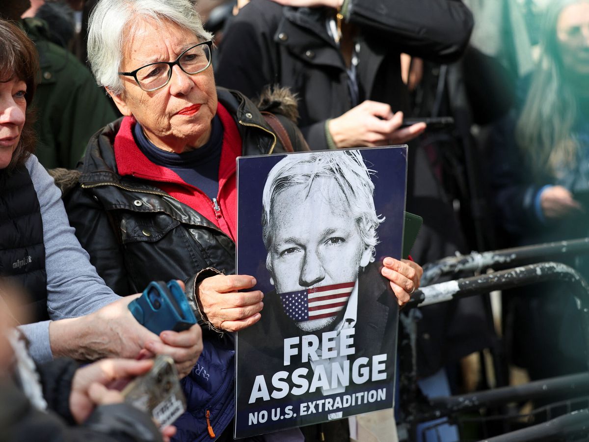 Foto: Una mujer sujetando un cartel en apoyo a Assange. (Reuters/Toby Melville)