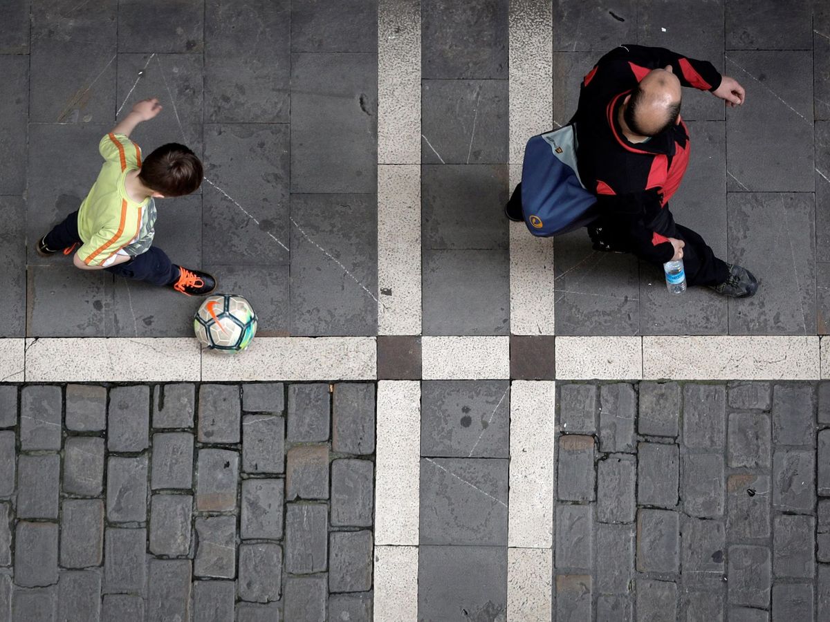 Foto: Un niño con un balón camina junto a un adulto en horario infantil. (EFE)