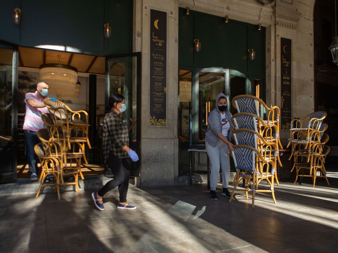 Dos trabajadores recogen la terraza de un bar del centro de Barcelona. (EFE)