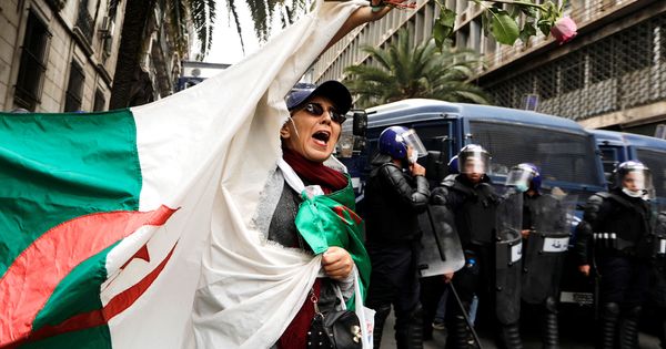 Foto: Policías montan guardia mientras una mujer agita una bandera argelina durante una protesta en Argel, el 8 de marzo de 2019. (Reuters)