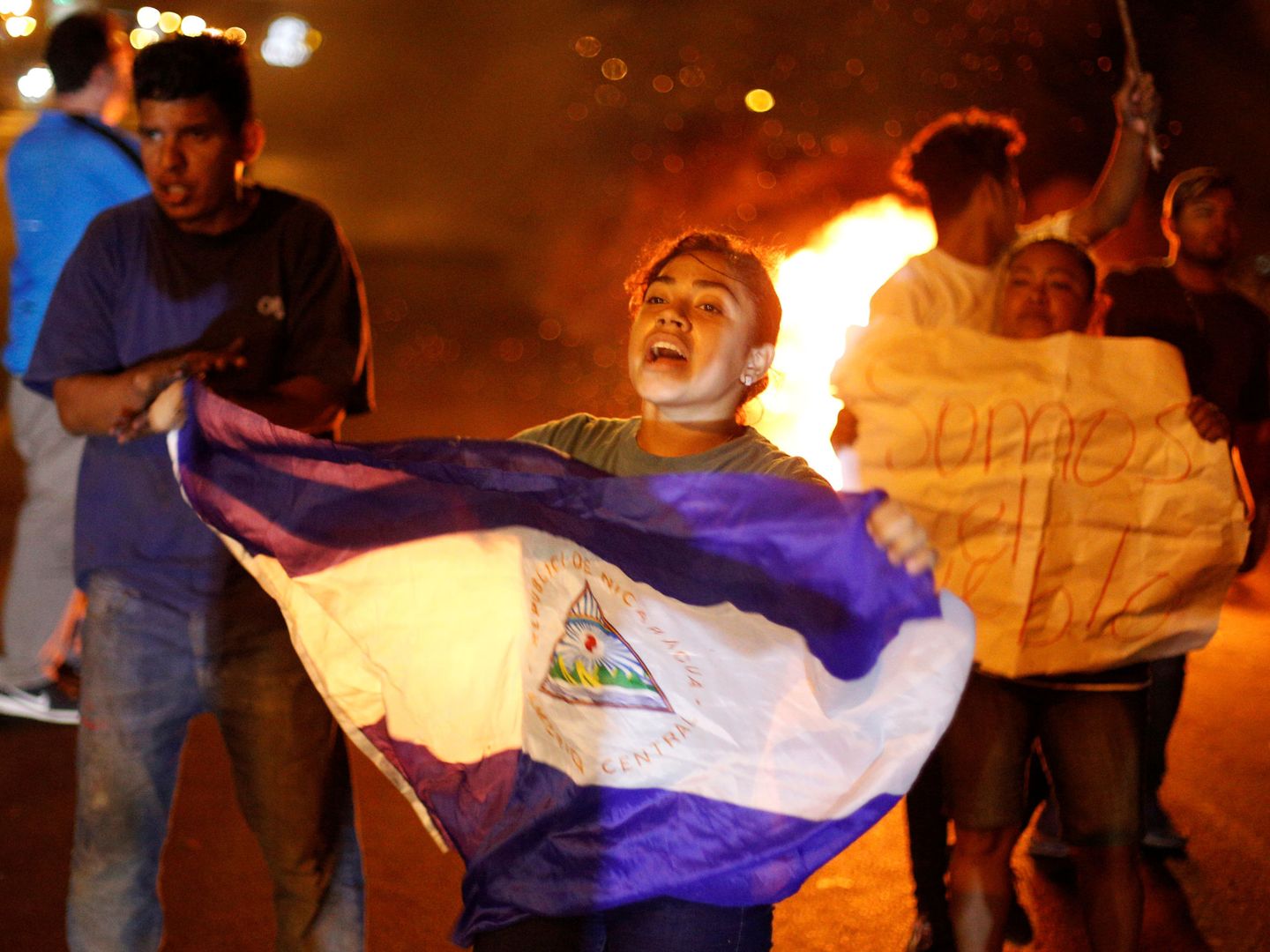 Una manifestante agita una bandera nicaragüense delante de una barricada en llamas. (Reuters)