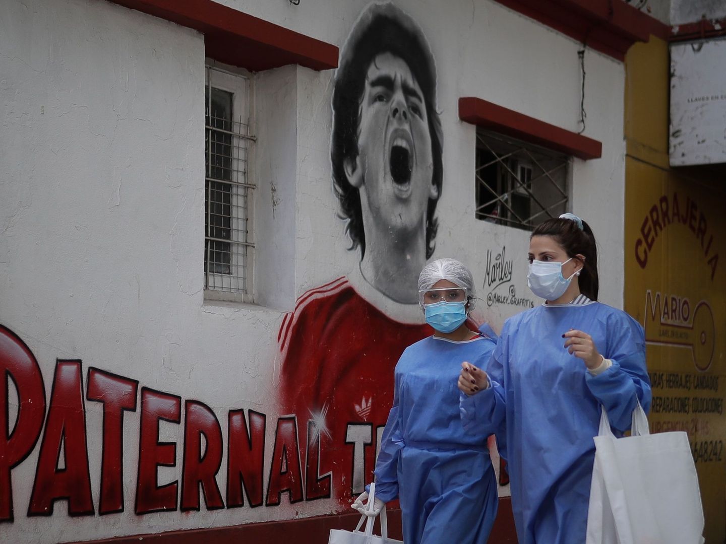 Dos trabajadoras de la salud caminan frente a un mural de Diego Maradona, el pasado 28 de octubre en Buenos Aires. (Efe)
