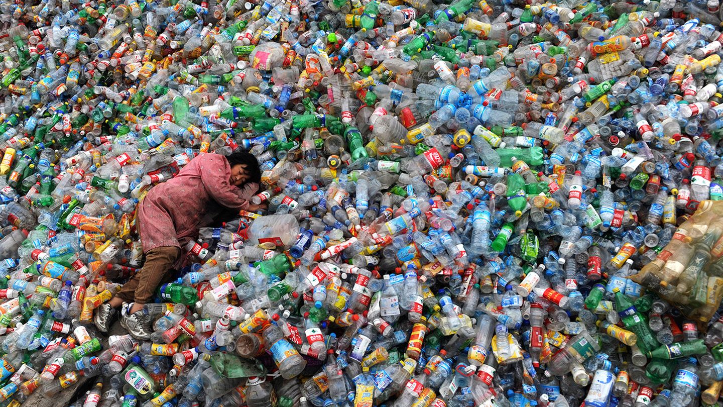 Un trabajador descansa sobre montañas de plásticos para reciclar. (Reuters)