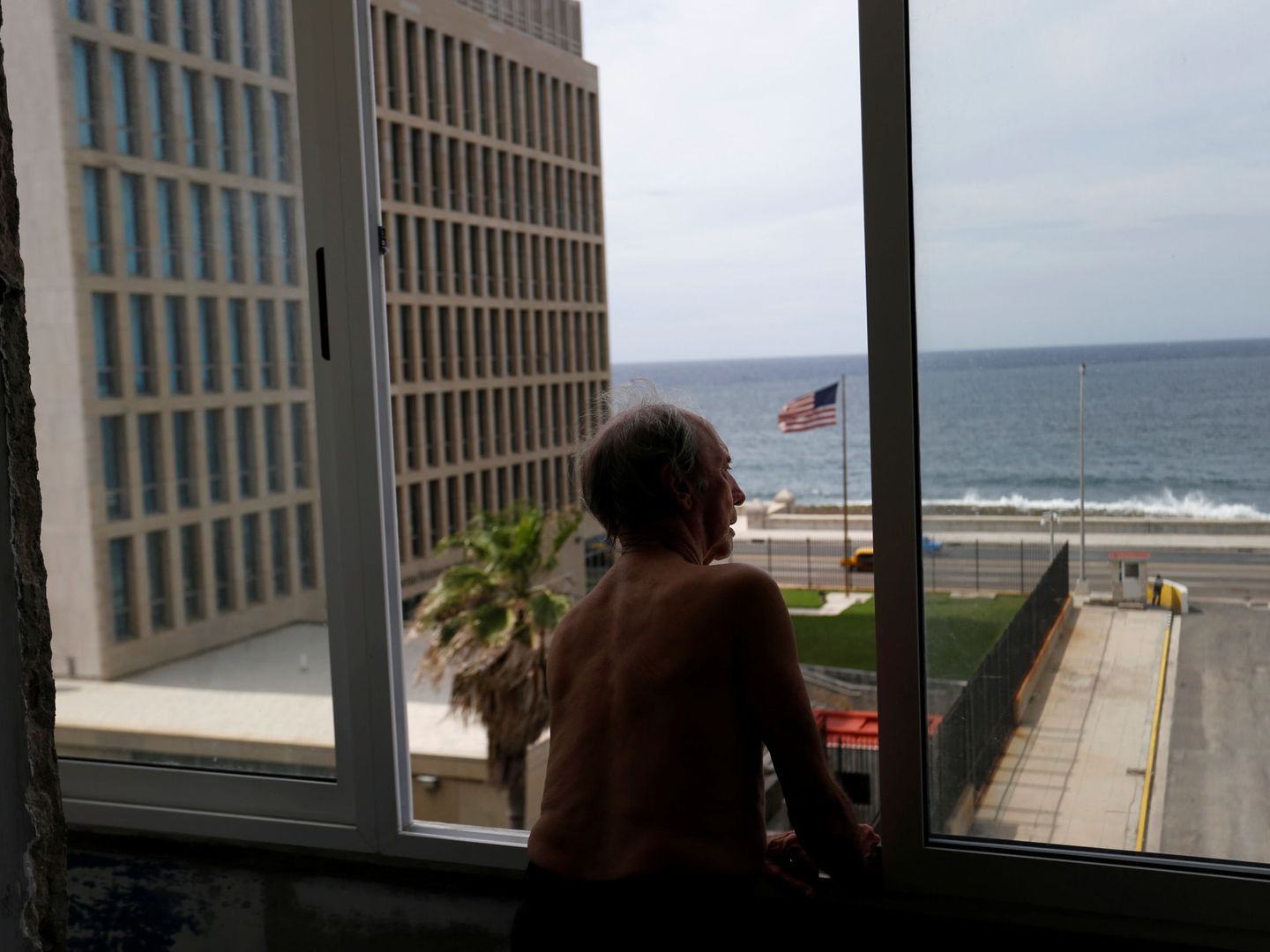 Un hombre mira por la ventana, con vistas a la Embajada de EEUU en La Habana, en junio de 2017. (Reuters)