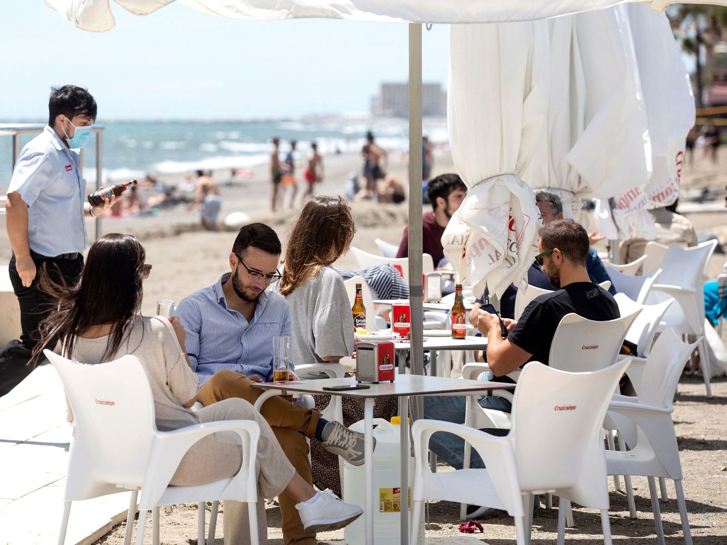 Varias personas disfrutan del buen tiempo en los chiringuitos de la playa de La Misericordia, de Málaga. (EFE/Daniel Pérez)