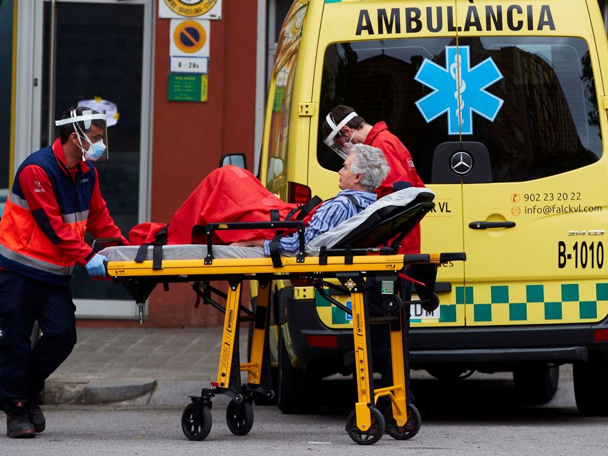 Foto: Operarios de una ambulancia transportan a un enfermo desde su domicilio en el centro de Barcelona. (EFE)