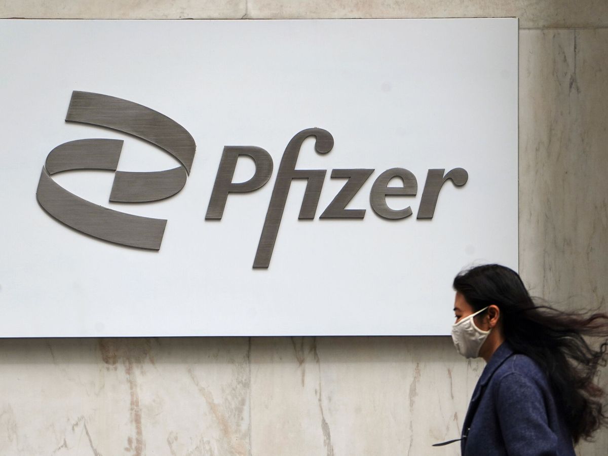 Foto: Una mujer pasa por delante del logo de Pfizer. (Carlo Allegri/Reuters)