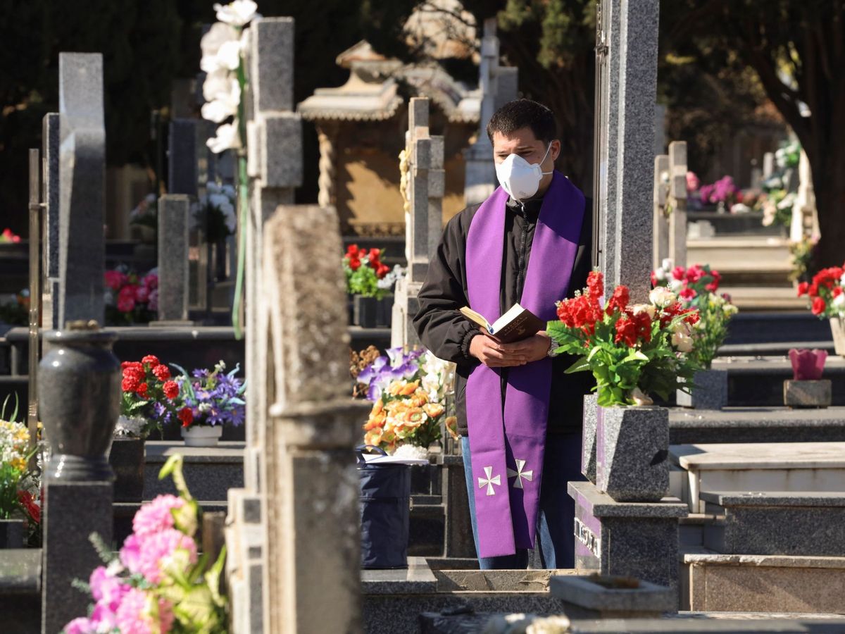 Foto: Un sacerdote hace un responso durante un entierro sin asistentes en el cementerio de Salamanca. (EFE)