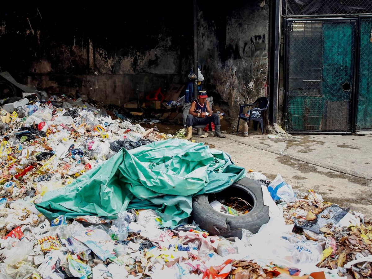 Foto: Un hombre descansa junto a basura en Caracas. (EFE)