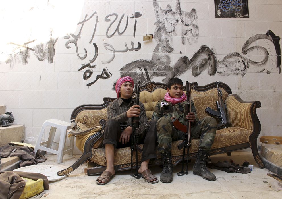 Foto: Dos jóvenes combatientes del Ejército Libre de Siria posan en la Ciudad Vieja de Alepo. En la pared se lee: "Dios, Siria, Libre". (Reuters)