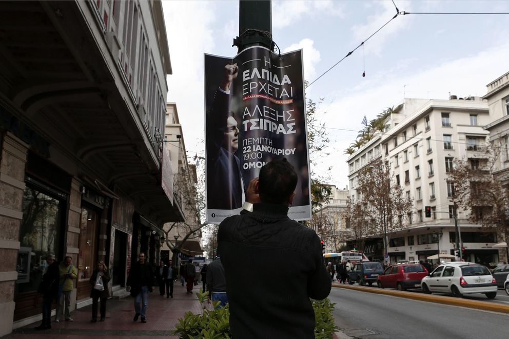 Un hombre coloca un póster electoral con la imagen del líder de Syriza, Tsipras, en Atenas (Reuters).