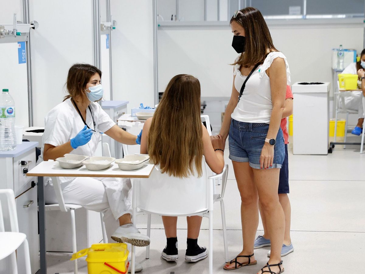 Foto: Una adolescente, acompañada de su madre, se vacuna contra el covid-19 en el hospital Enfermera Isabel Zendal de Madrid. (EFE) 