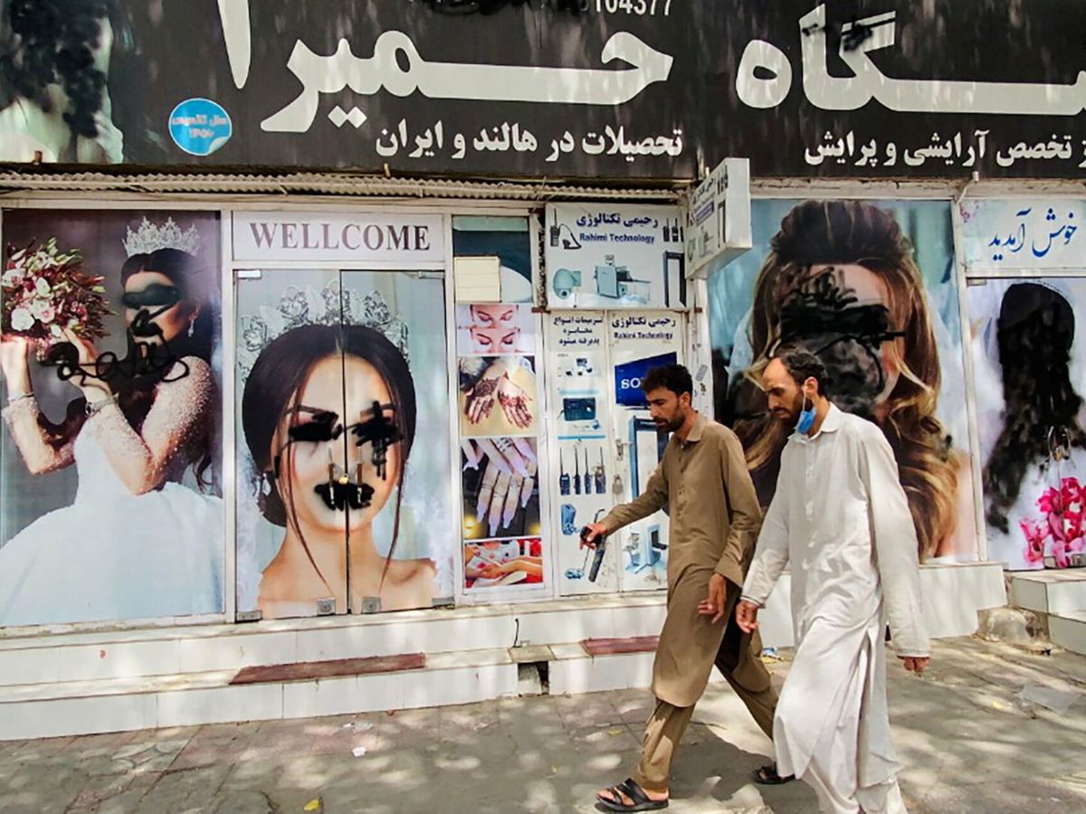 Foto: Dos hombres pasan ante un salón de belleza en Kabul. (EFE)