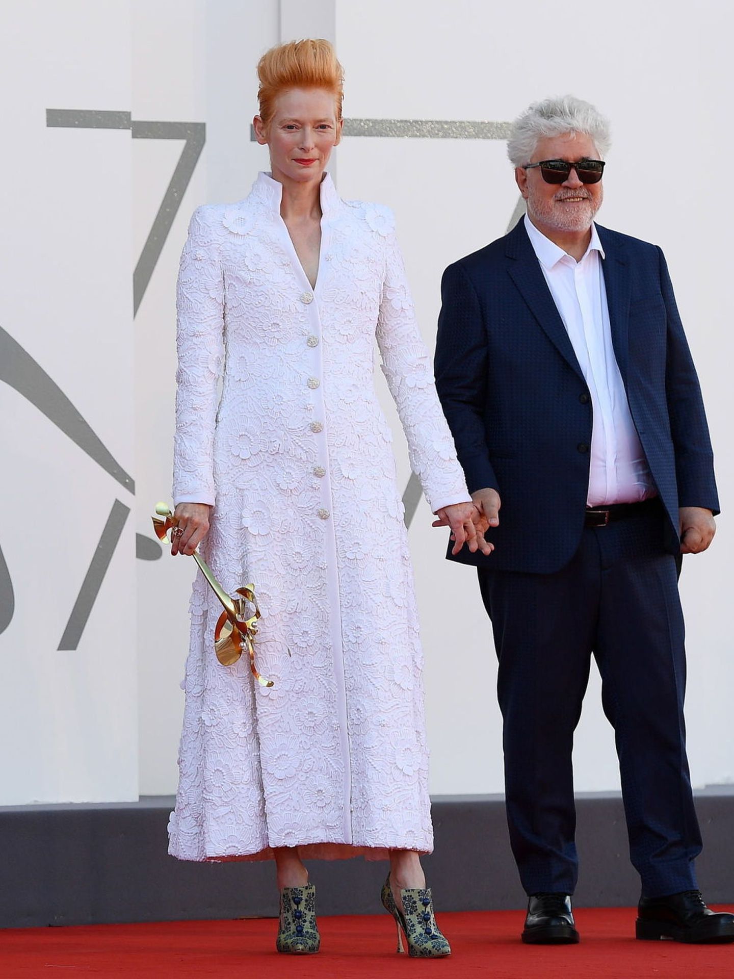 Pedro Almodóvar, con traje azul marino y camisa blanca, junto a Tilda Swinton, con vestido blanco de Chanel, en la presentación de 'The Human Voice'. (EFE)