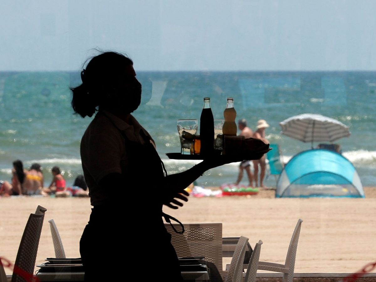 Foto: Una camarera lleva una bandeja con bebidas en un restaurante de la playa de la Malvarrosa. (EFE/Kai Försterling)