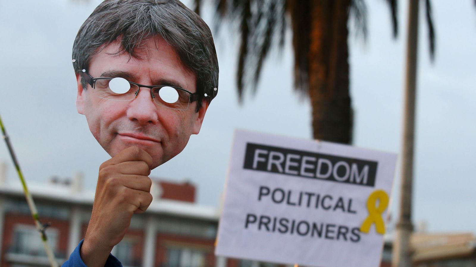 Foto: Un hombre alza una careta de Puigdemont durante una manifestación a favor de la libertad de los políticos presos. (Reuters)