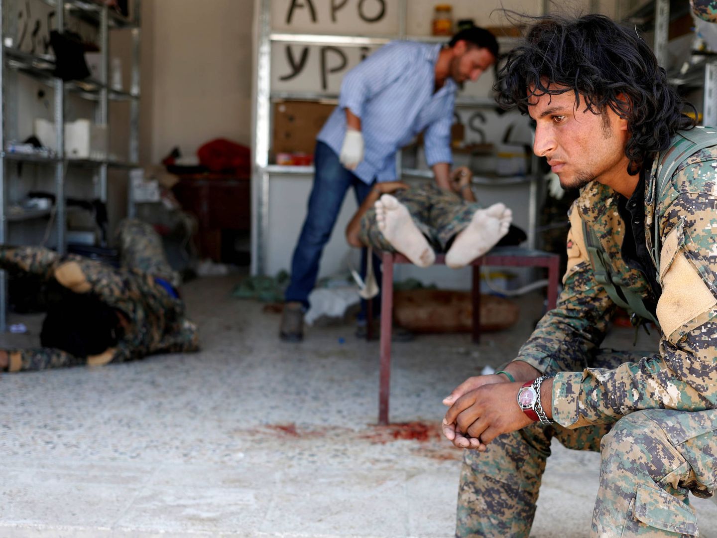 Un miliciano de las Fuerzas Democráticas Sirias ante varios camaradas heridos en combates contra ISIS, en Raqqa. (Reuters) 