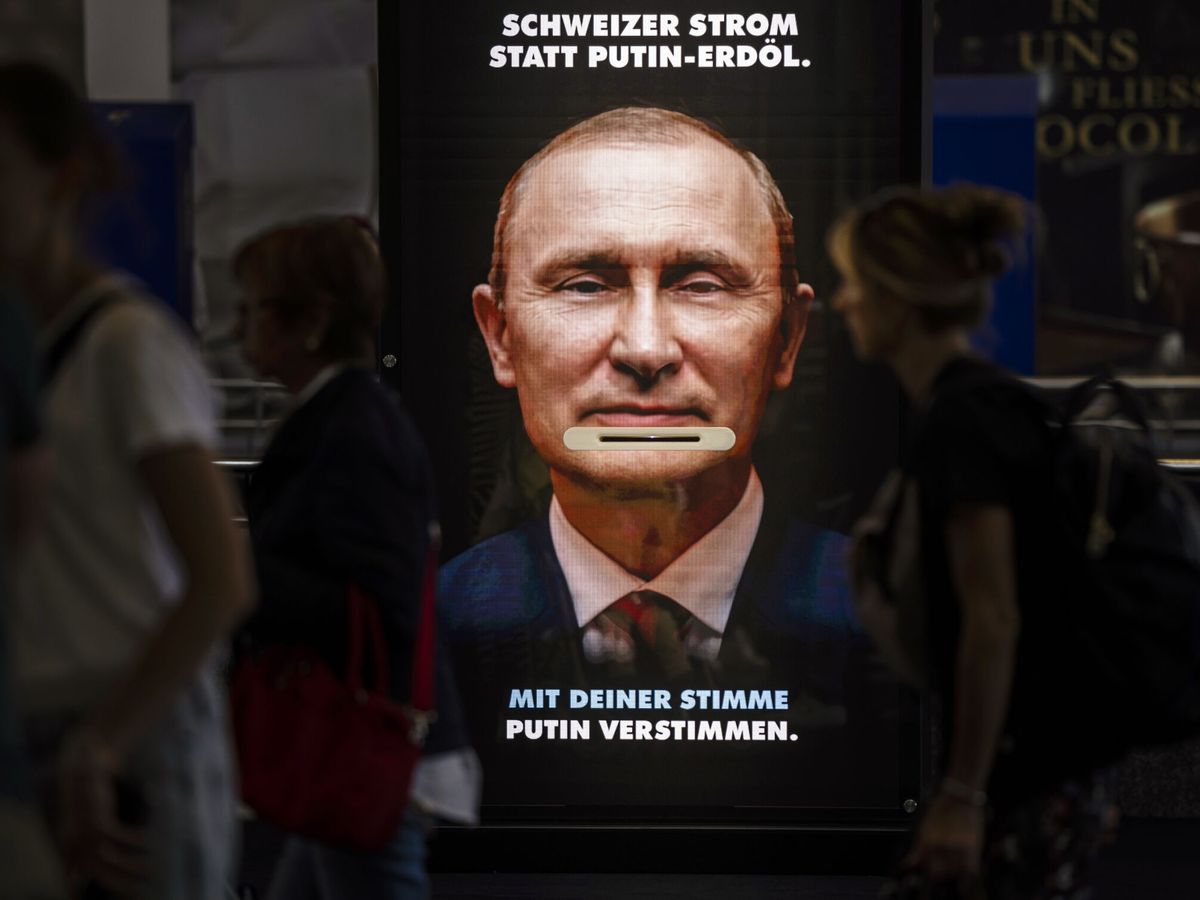 Foto: Varios transeúntes pasan junto a una pantalla de promoción de un referéndum acerca de la ley climática que muestra al presidente ruso. (EFE/Michael Buholzer)