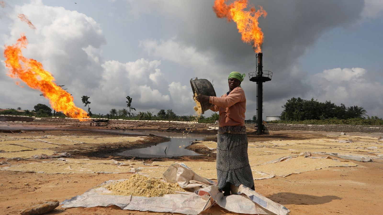 Una mujer vacía un bol de tapioca cerca de una planta de 'gas flaring' en el estado de Delta, Nigeria. (Reuters/Afolabi Sotunde)