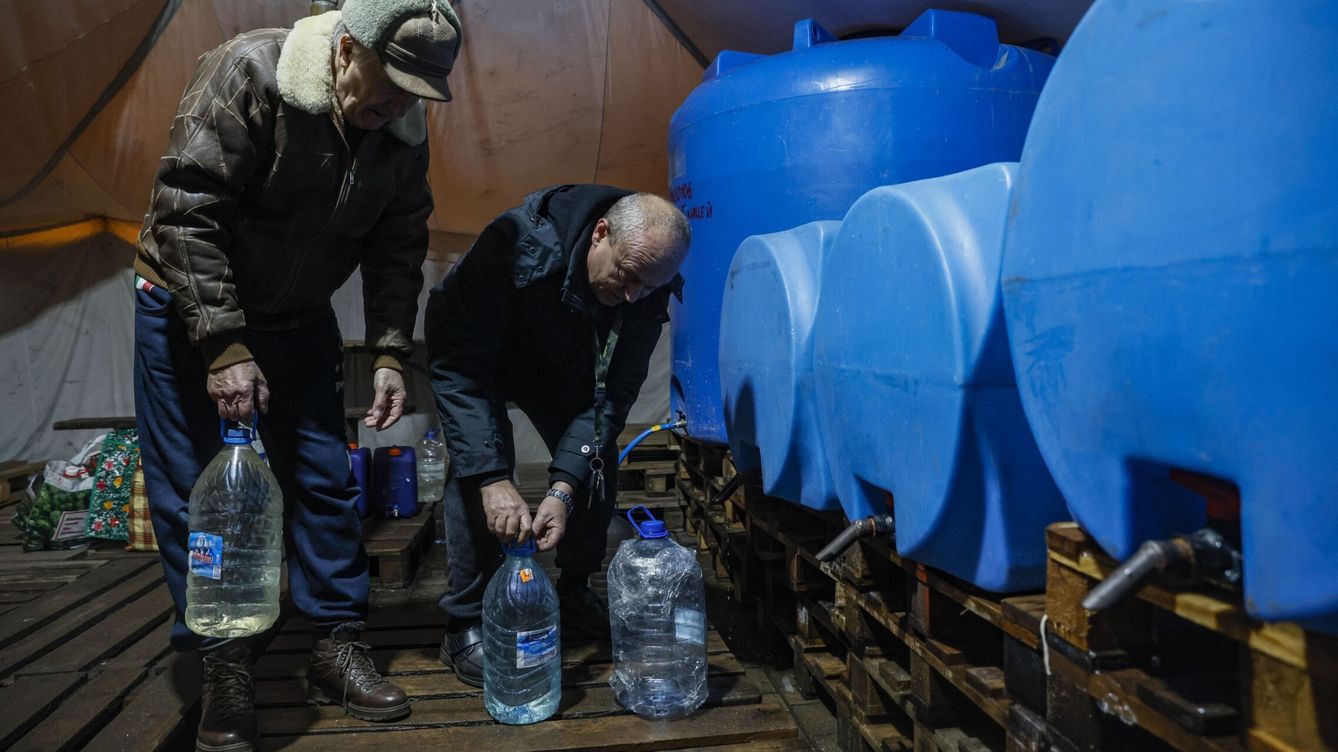 Foto: Dos hombres recargan agua en garrafas en la ciudad ucraniana de Donetsk. (EFE/Epa Sergei Ilnitsky)