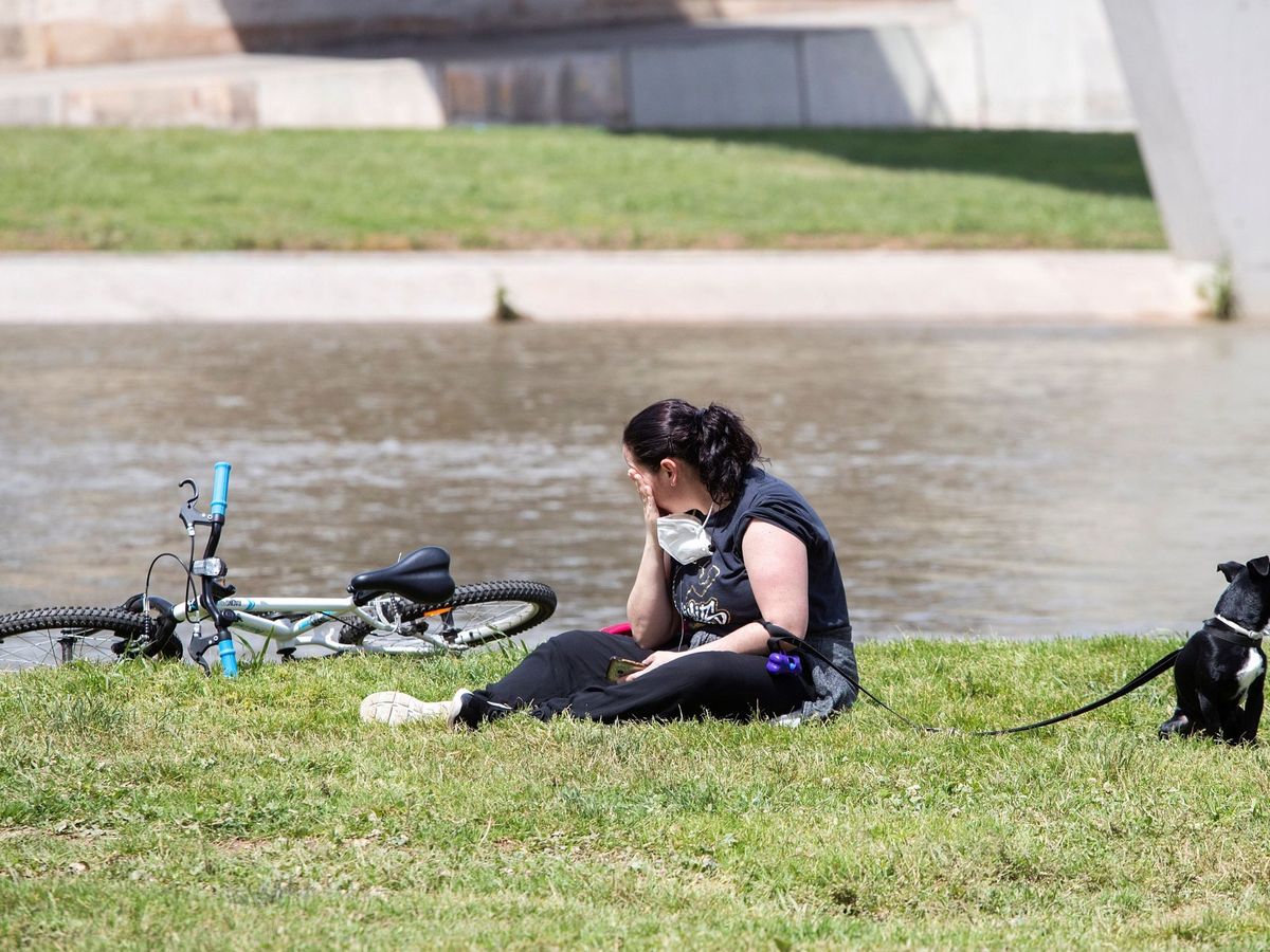Foto: Una mujer y su perro descansan en el parque fluvial del Besós. (Efe)